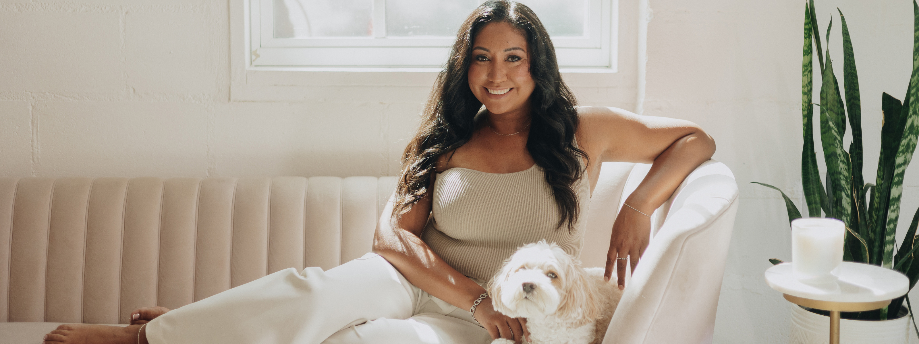 Luminosa_Vida_Owner_Yill_Wehrenberg_Sitting_on_a_Couch_with_a_nontoxic_candle_and_her_cavapoo_Kobe