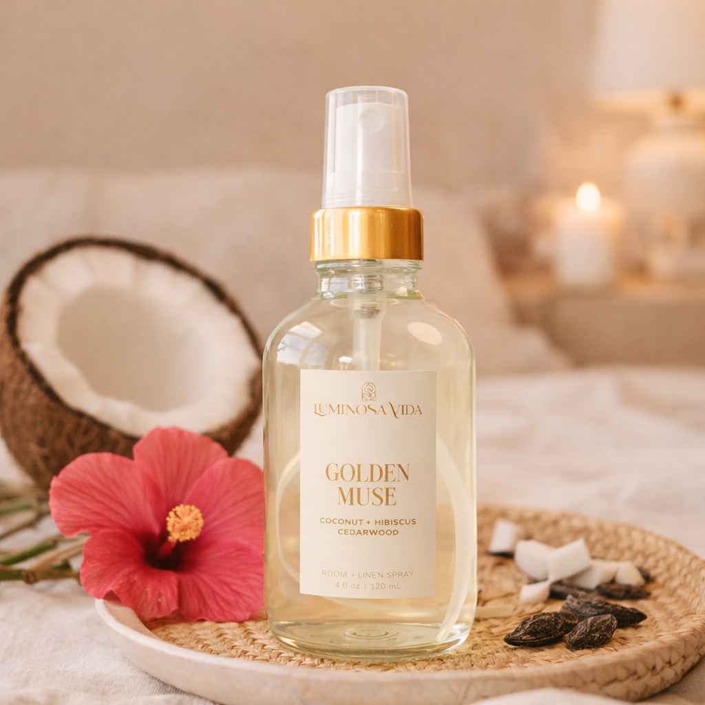 Luminosa Vida Golden Muse room and linen spray with coconut, hibiscus, and cedarwood styled with coconut and hibiscus flowers.