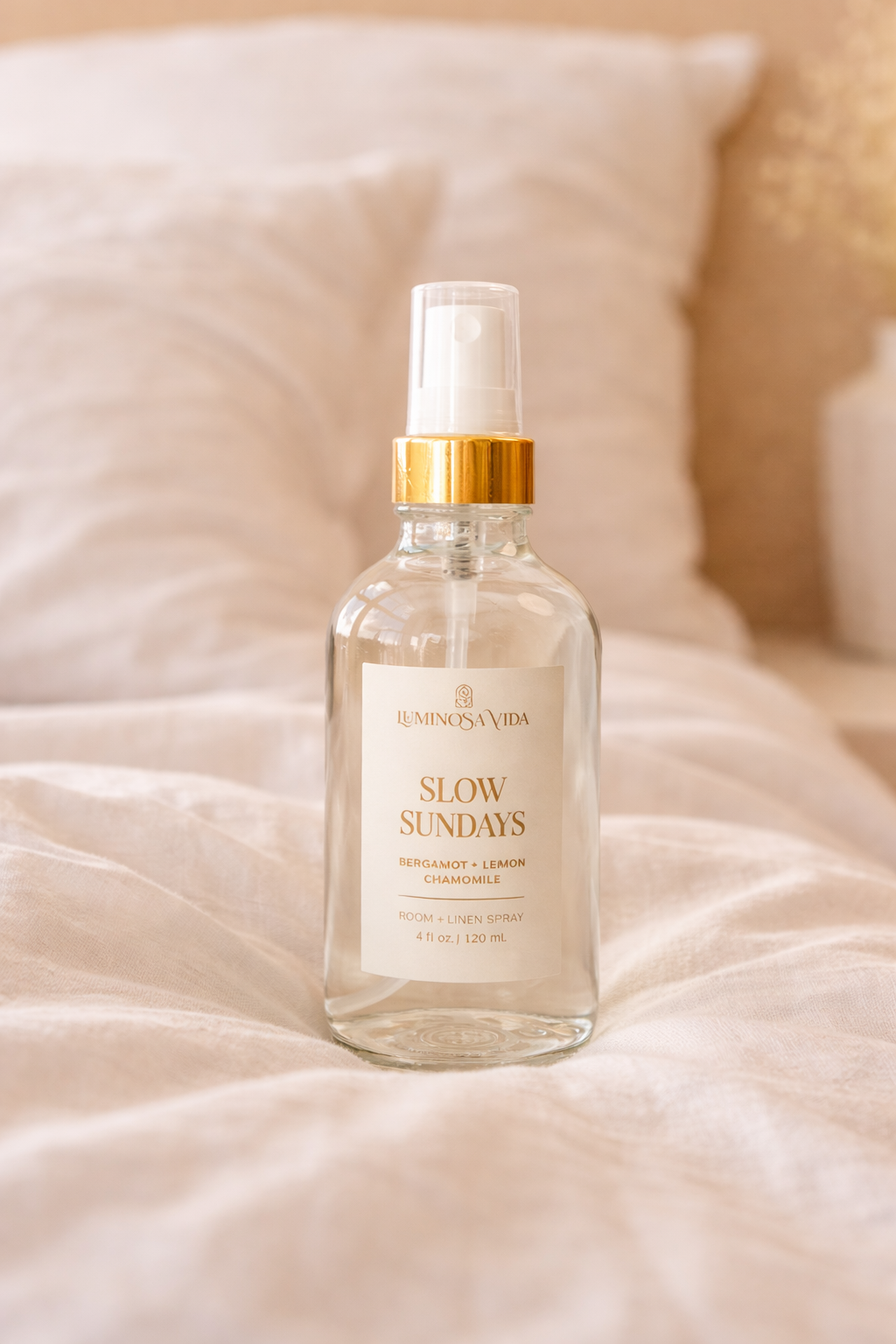 Luminosa Vida Slow Sundays room and linen spray with bergamot, lemon, and chamomile placed on soft bedding in a warm bedroom lifestyle setting.