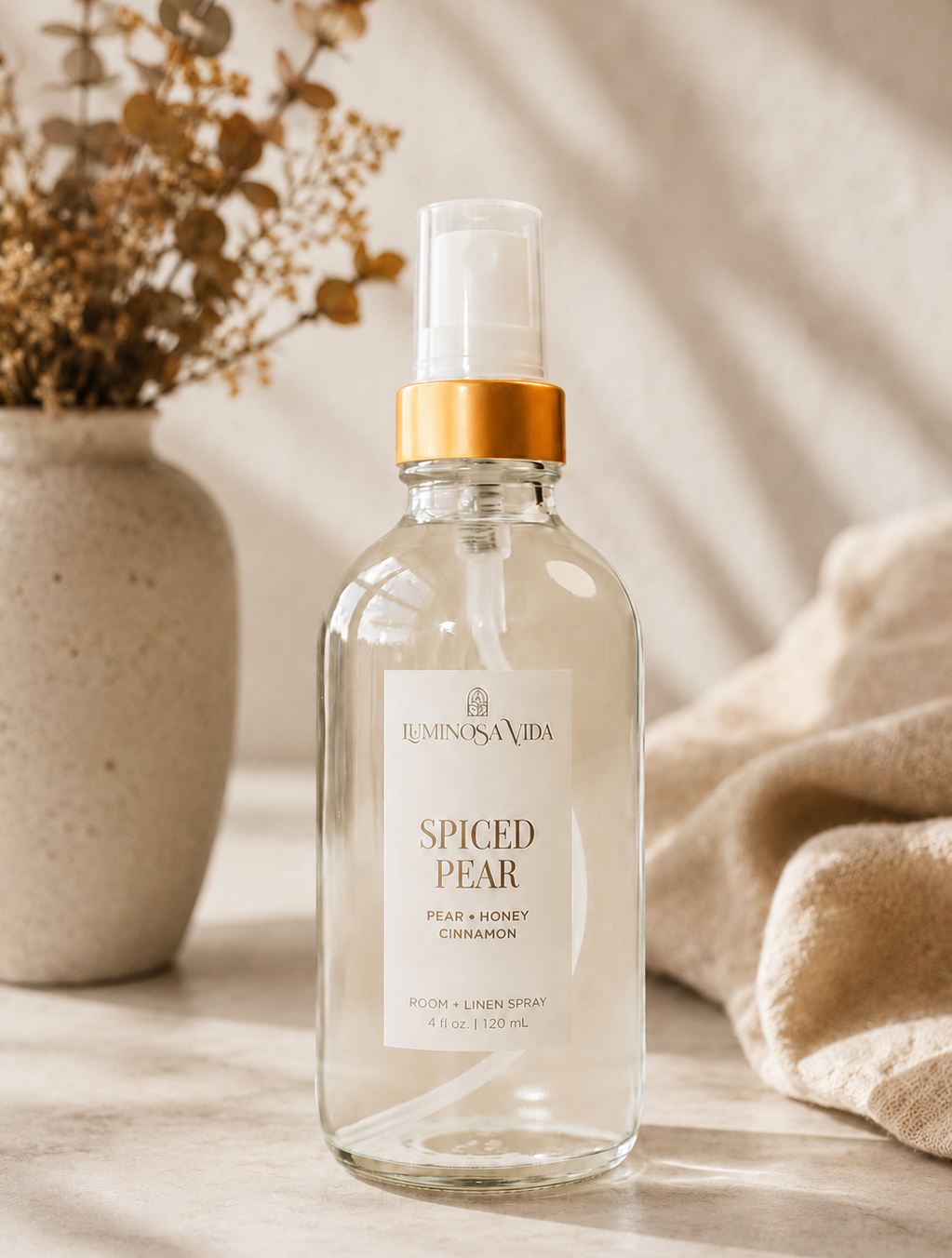 Luxury Spiced Pear Room & Linen Spray by Luminosa Vida in a cozy fall home setting featuring pear, honey, and cinnamon notes. Clean, phthalate-free home fragrance for refreshing linens, bedding, and living spaces.