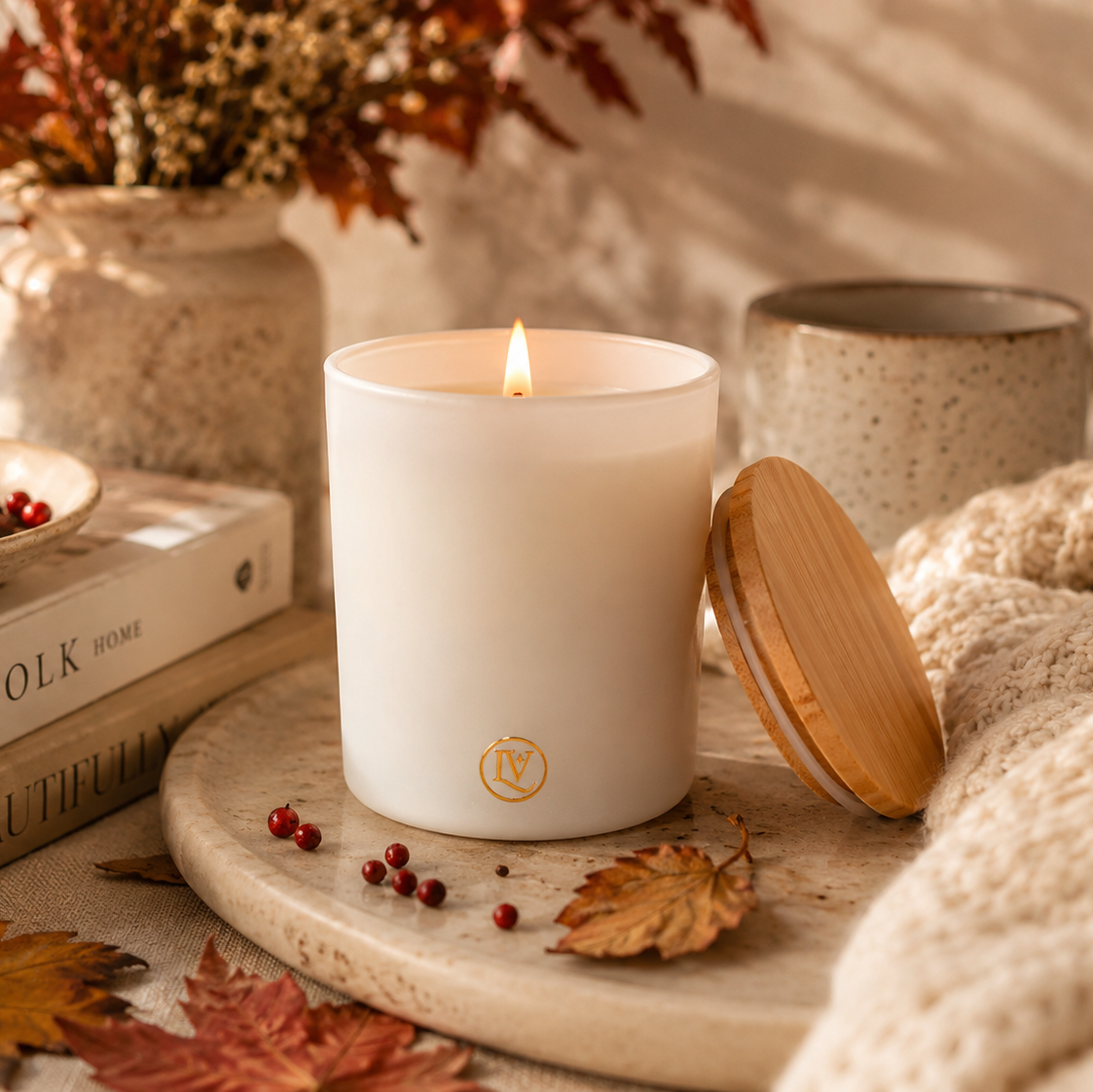 Autumn Dreams fall candle by Luminosa Vida styled on a marble tray with a cozy knit blanket, autumn leaves, books and a ceramic mug. Luxury coconut wax candle with notes of vanilla, amberwood, warm woods, berries and pink pepper.