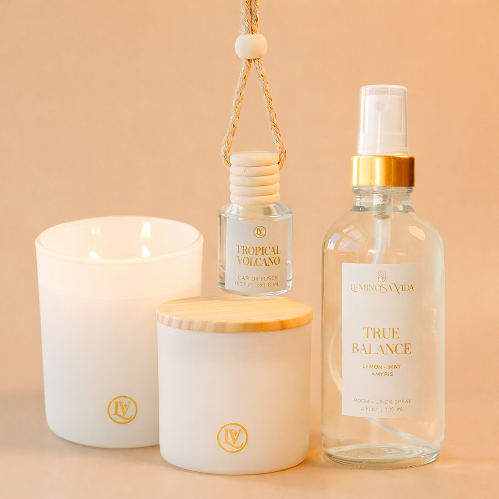 Luminosa Vida luxury home fragrance products including coconut wax candle, Tropical Volcano car diffuser, and True Balance room and linen spray with lemon, mint, and amyris.