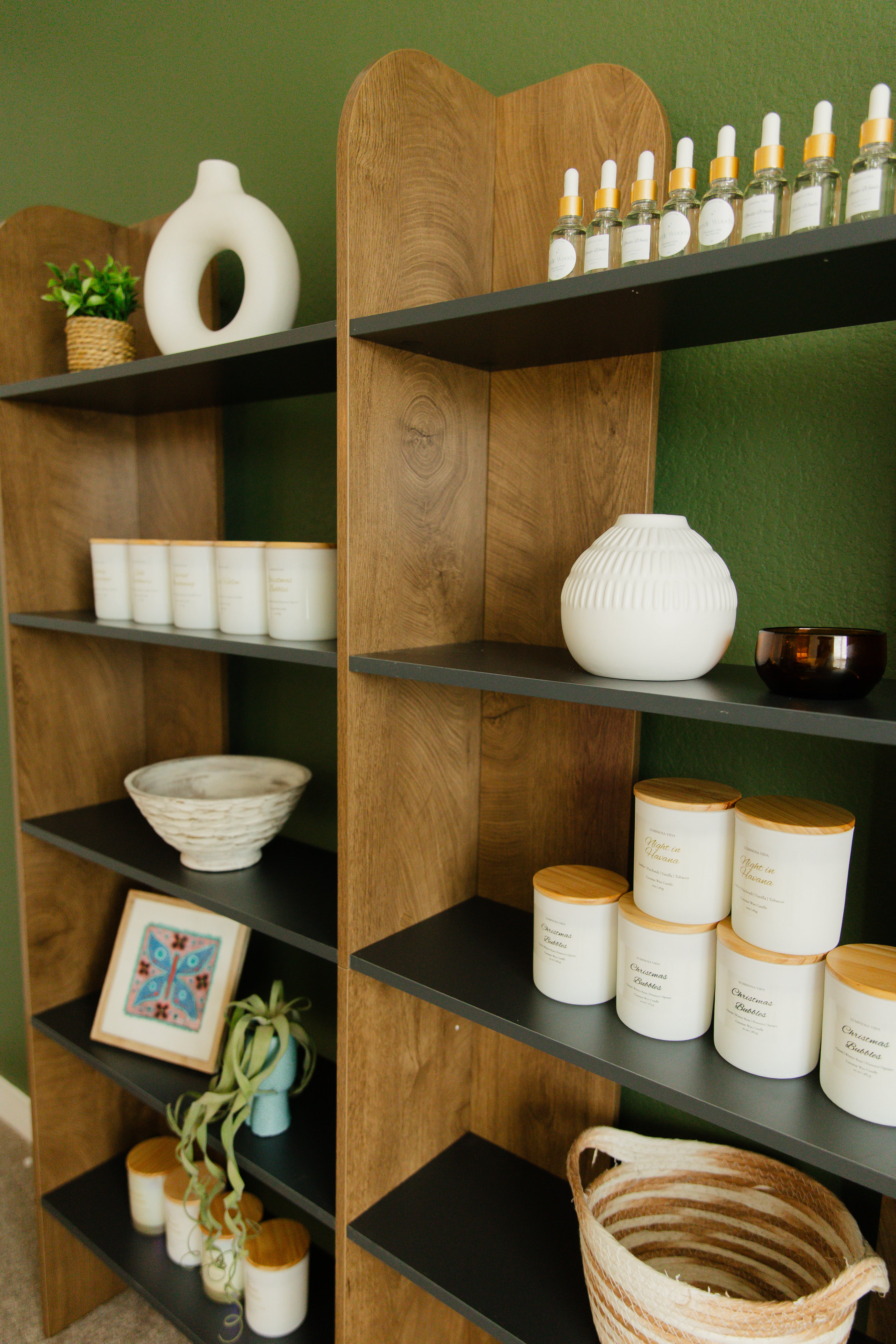 Luminosa Vida candles styled on modern wooden shelves with home decor accents featuring coconut wax candles and room sprays in a warm interior setting