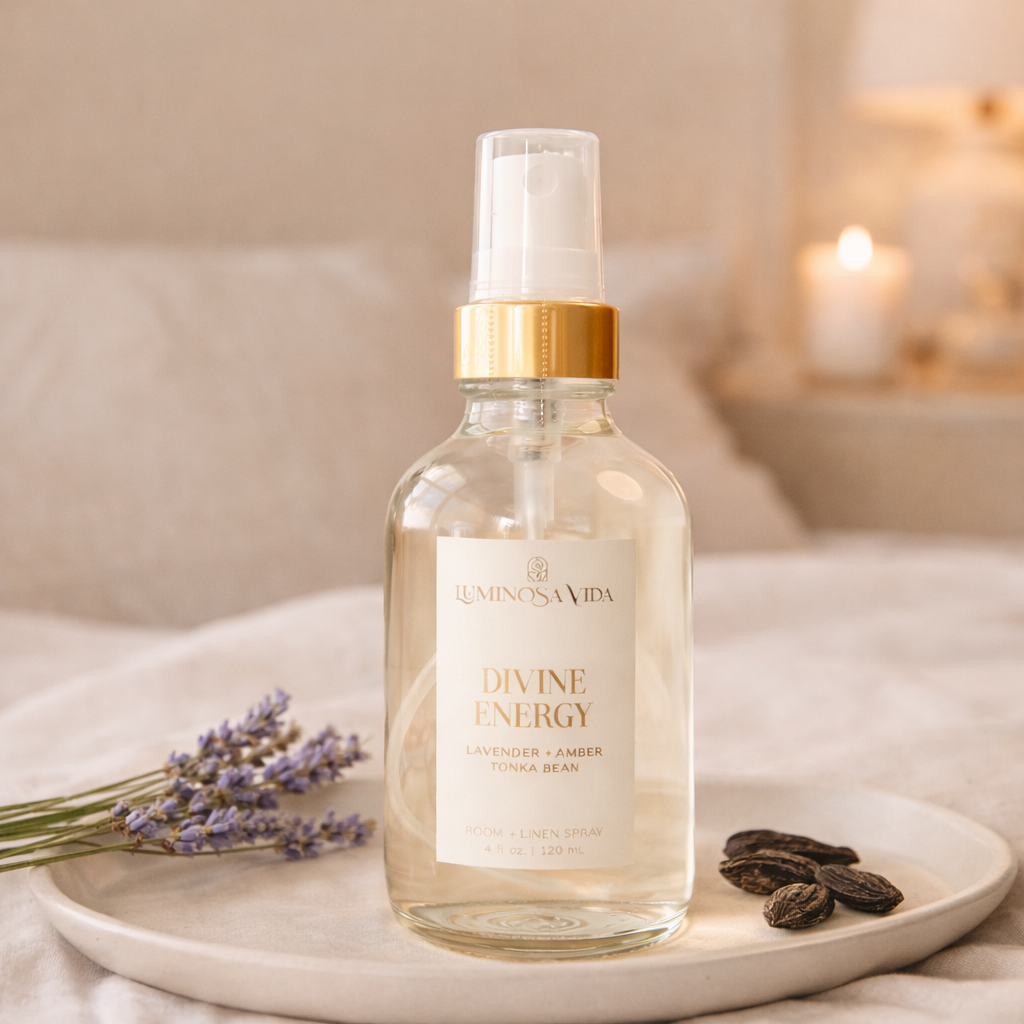 Luminosa Vida Divine Energy room and linen spray with lavender, amber, and tonka bean styled on a ceramic tray with lavender sprigs.