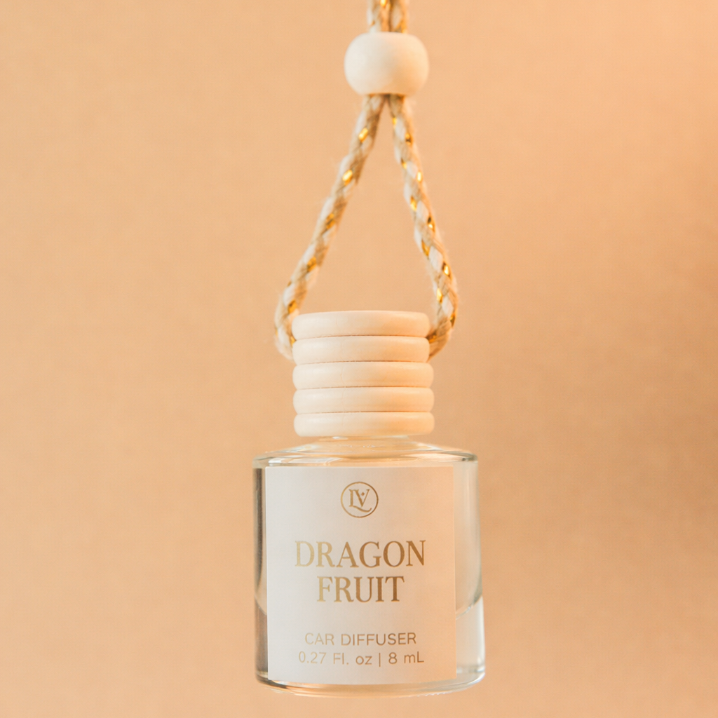 Luminosa Vida Dragon Fruit hanging car diffuser with braided cord in a warm neutral lifestyle setting.