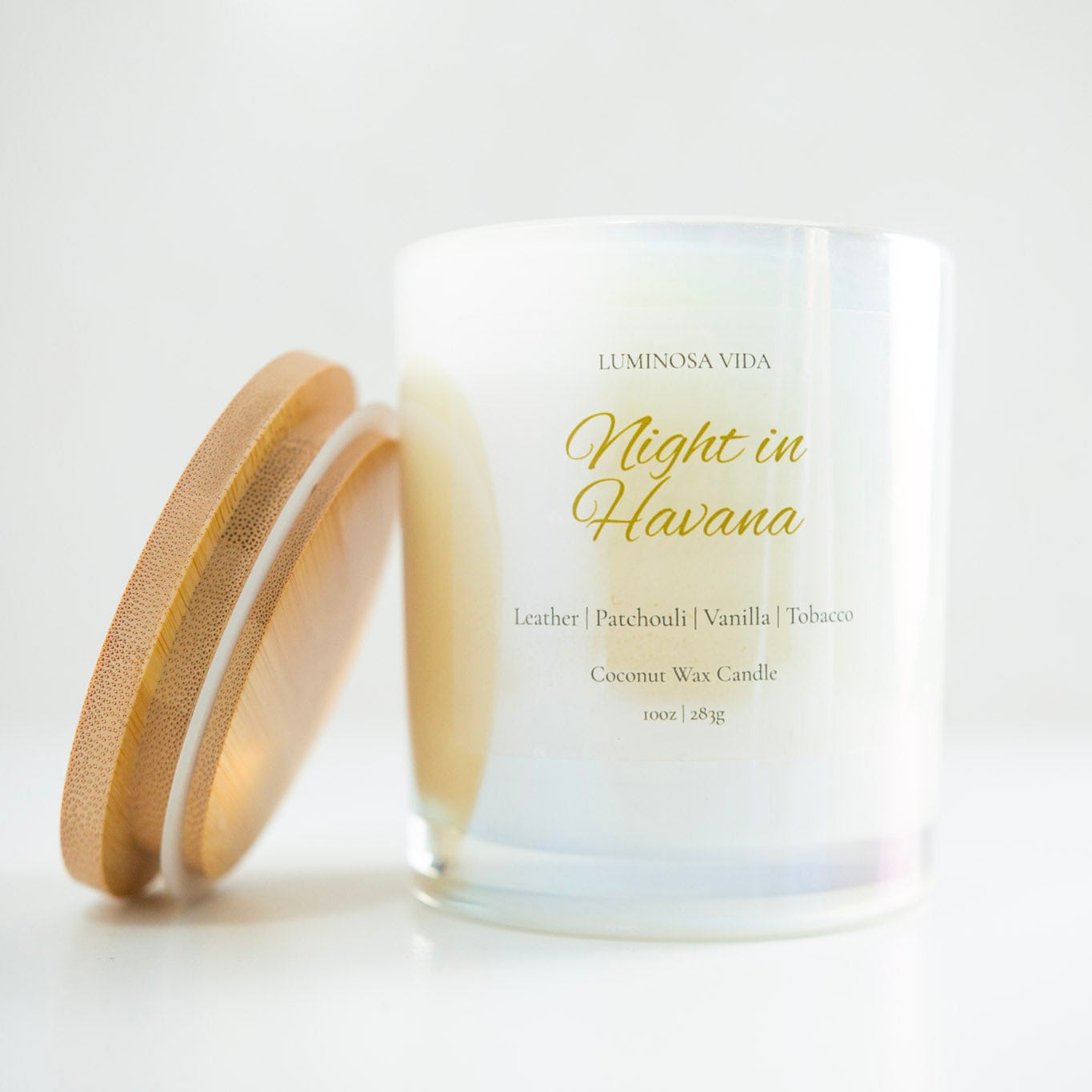 “Luminosa Vida Night in Havana candle in an iridescent glass jar with a wooden lid. Luxury coconut wax candle handcrafted in Austin, Texas with notes of leather, patchouli, vanilla, and tobacco — a warm, sensual, and sophisticated scent.”