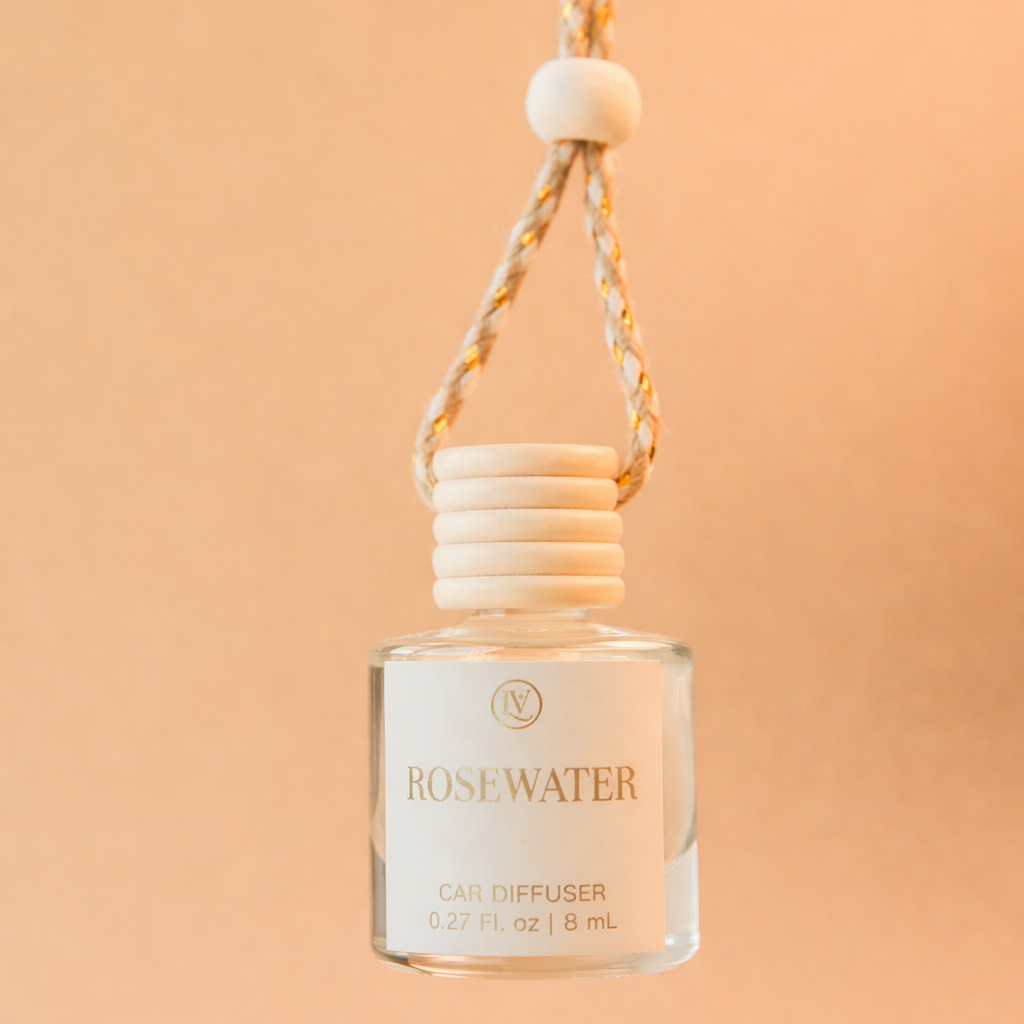 Luminosa Vida Rosewater hanging car diffuser with braided cord in a warm neutral lifestyle setting.