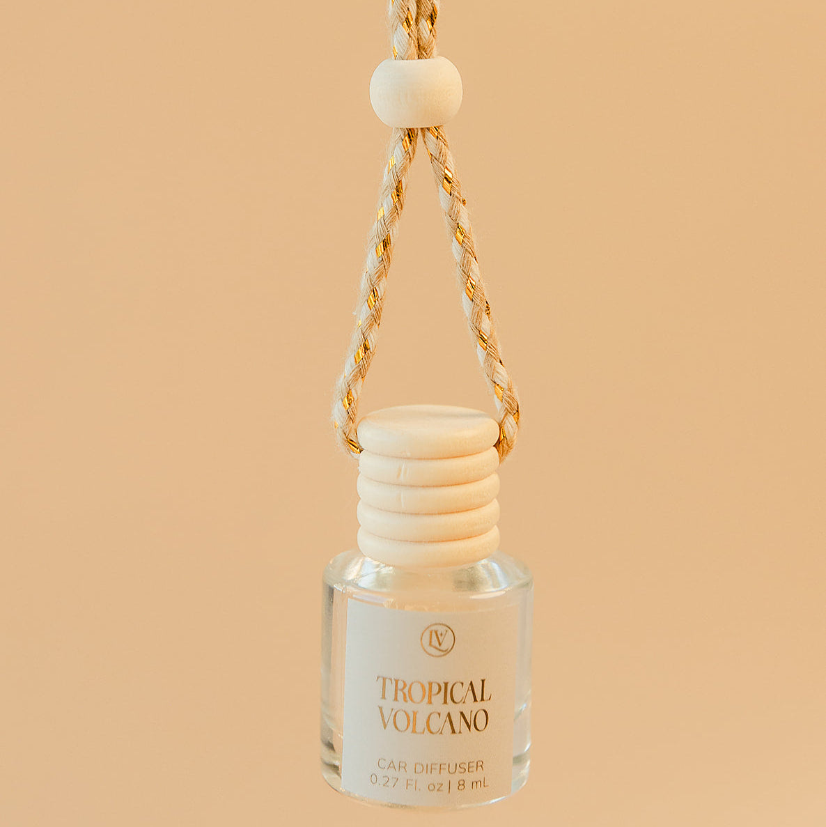 Luminosa Vida Tropical Volcano car diffuser hanging with braided cord in a warm neutral lifestyle setting.