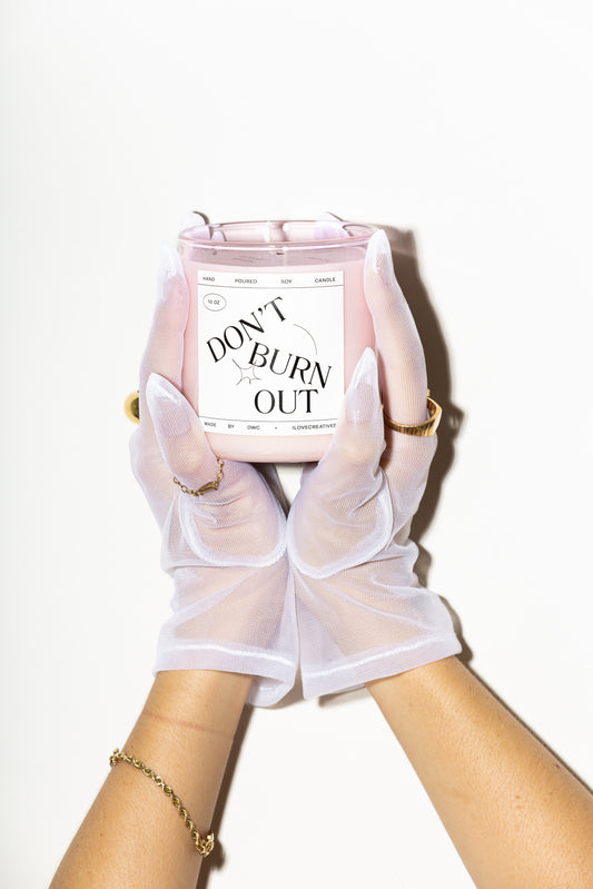 woman holding a candle that says don't burn our, gloved hands, feminine, rings, nails